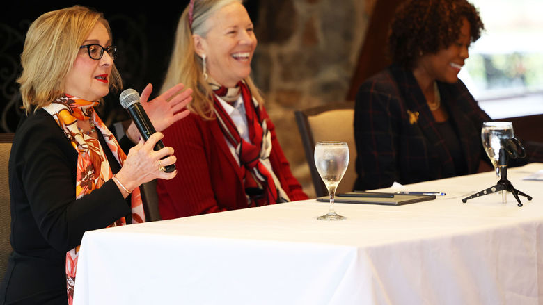 Three women sit at a table facing the audience.