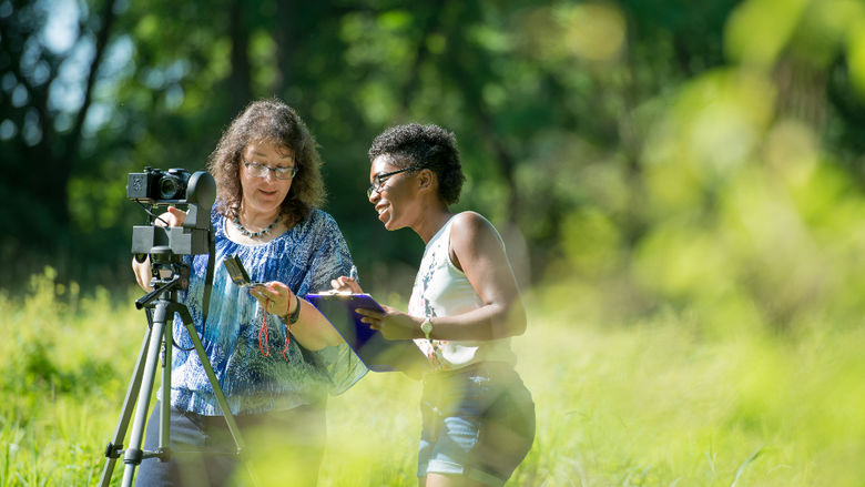 Professor and student conducting research outside.