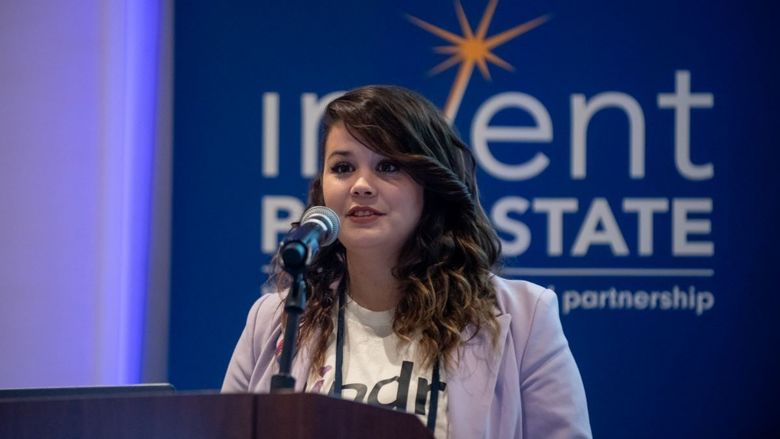 Mary Richardson speaks at podium in front of Invent Penn State signage during the Student Startup Showcase at the Invent Penn State Venture & IP Conference.