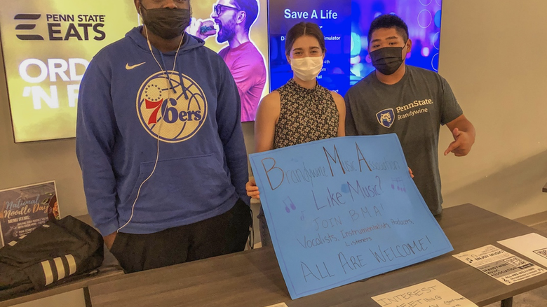 Three people wearing masks holding a sign to join BMA