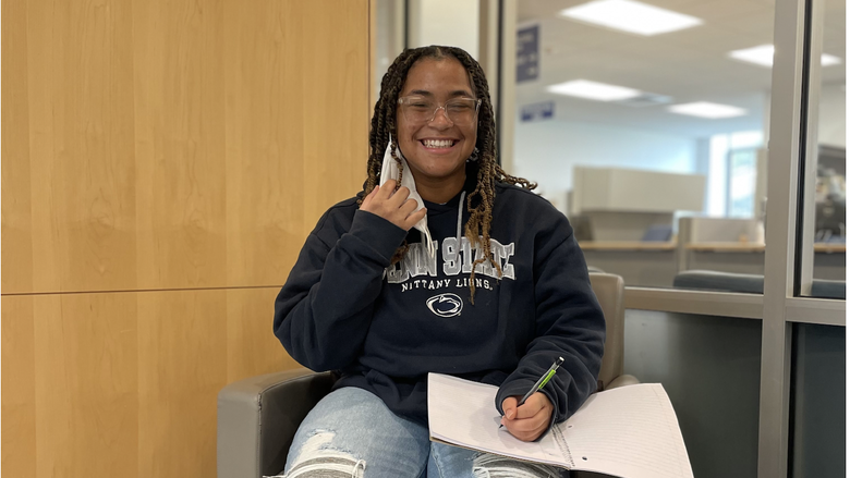 Students Sierra Coleman sits in a chair writing