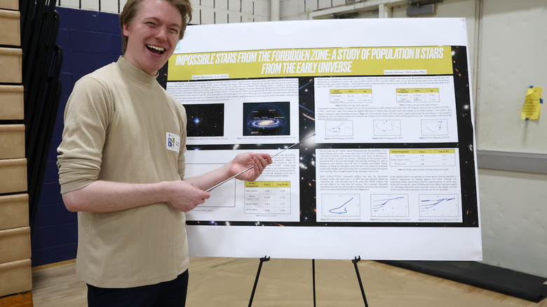 Student holding pointer while presenting poster on stars