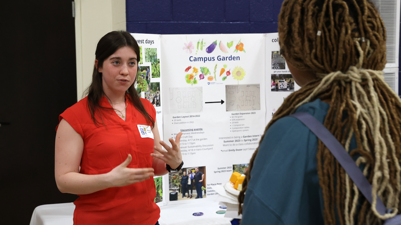 Student explaining campus garden poster to student