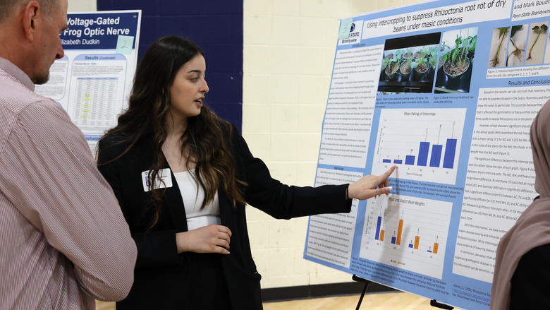 Student presenting work on poster to two people