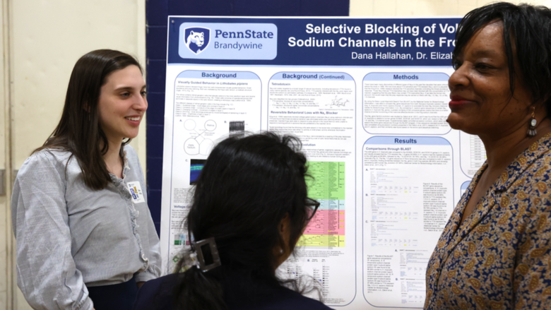 Student explaining research to two guests