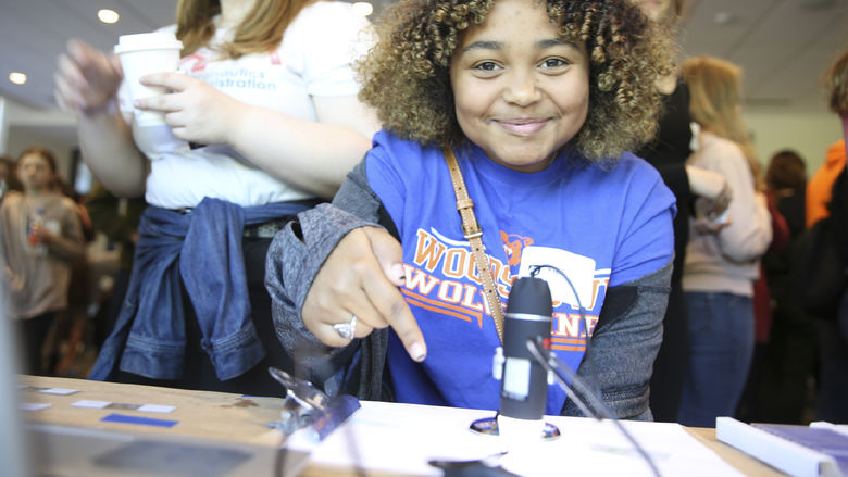 A girl points to a microscope slide.