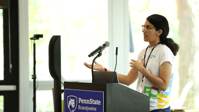 A woman speaks to an audience next to a lectern.