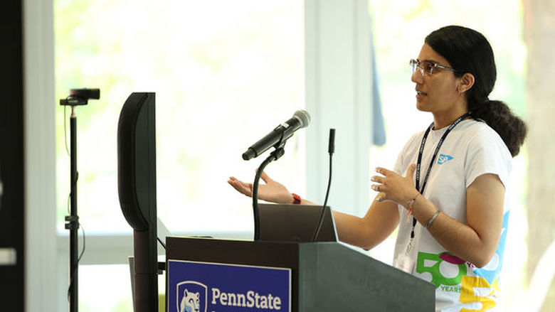 woman wearing glasses standing at a podium with microphone
