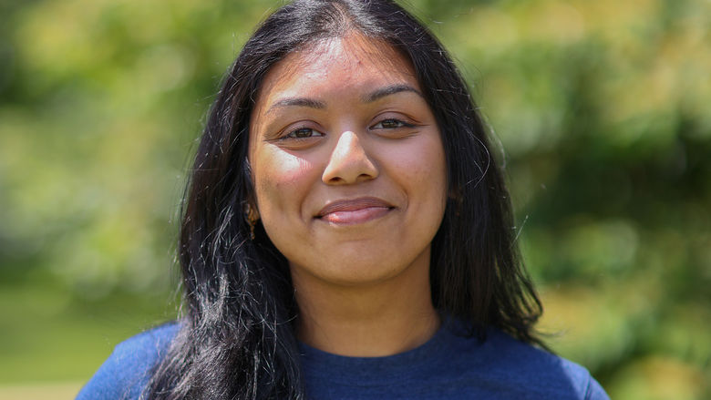 woman smiling, standing in front of trees