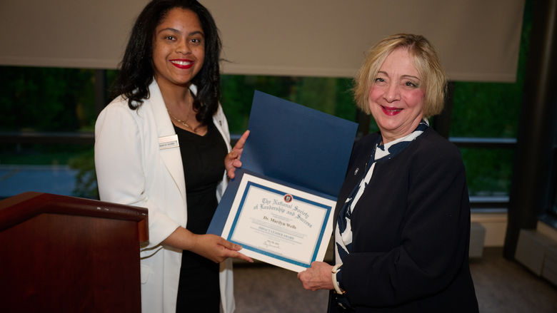woman holding certificate and standing next to woman