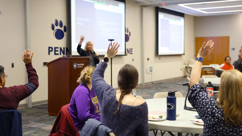 Members of the REAL raising their hands at a Town Hall meeting to show who is involved