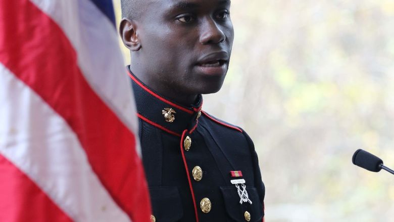 Veteran speaking and standing next to american flag