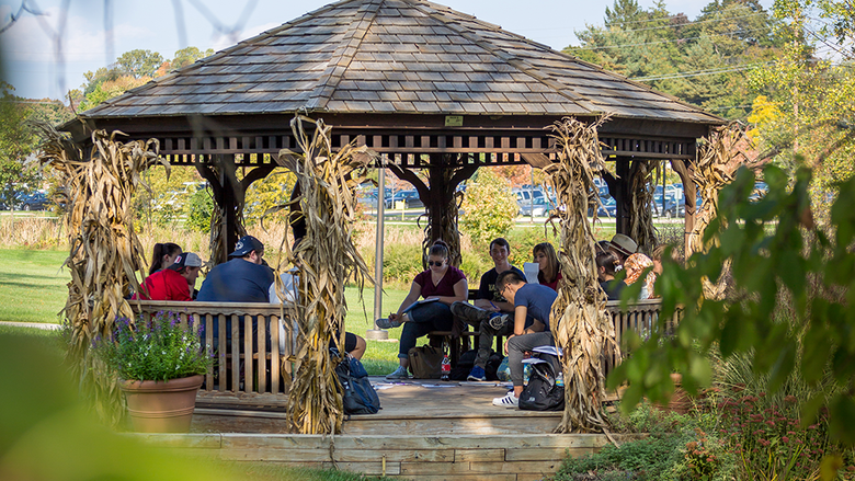 Students sitting in gazebo on campus.