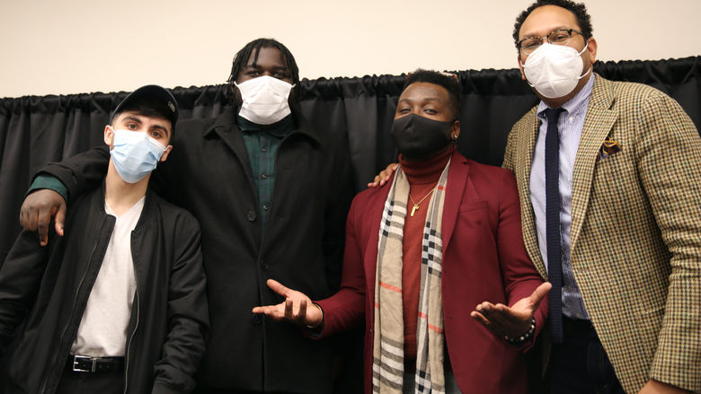 Four men stand with their masks on
