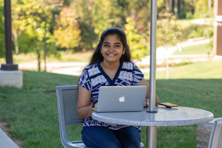 Renusree Bandaru studying outdoors at the Penn State Brandywine campus. 
