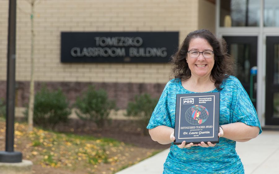 Laura Guertin stands outside with her award plaque.