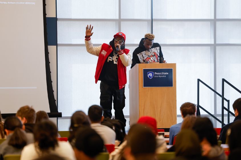 Philadelphia Freeway and DJ Crazy on stage with a large crowd of high schoolers