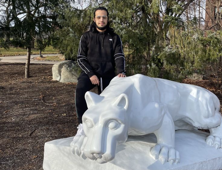 Student stands next to the lion shrine on the Penn State Brandywine campus.
