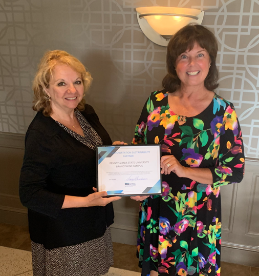 Two women hold up certificate at ceremony