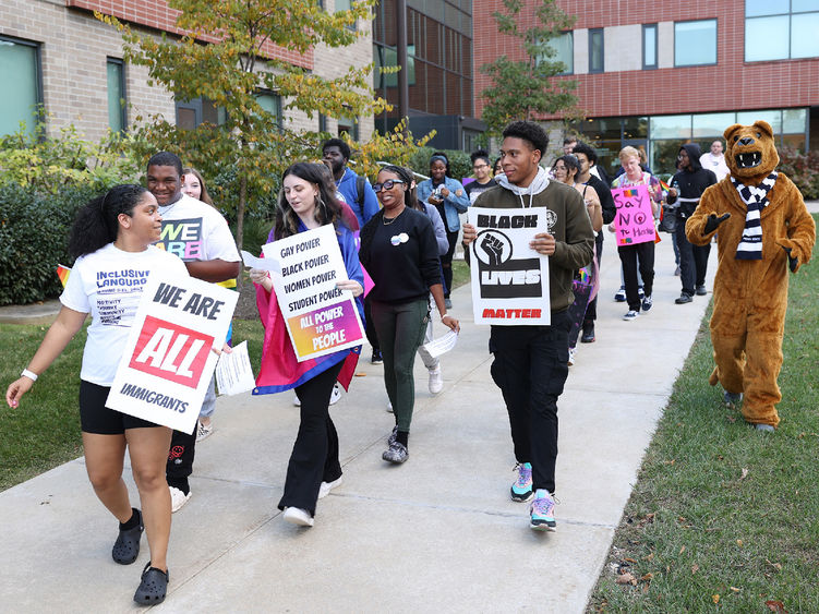 Students walk on campus carrying signs that support diversity, equity and inclusion.