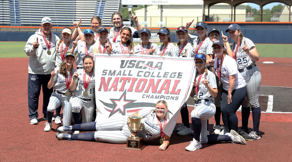 2023 Penn State Brandywine softball team posing with its championship banner and trophy