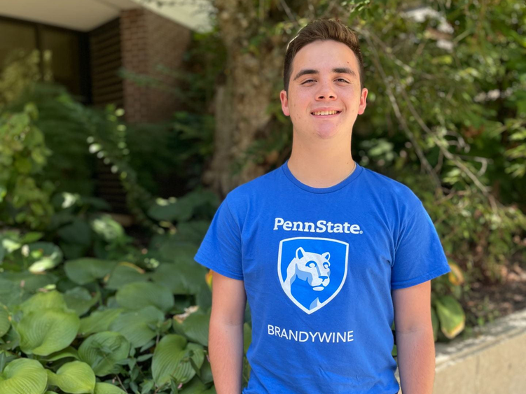 Cortez wearing a blue Brandywine shirt smiling in front of plants