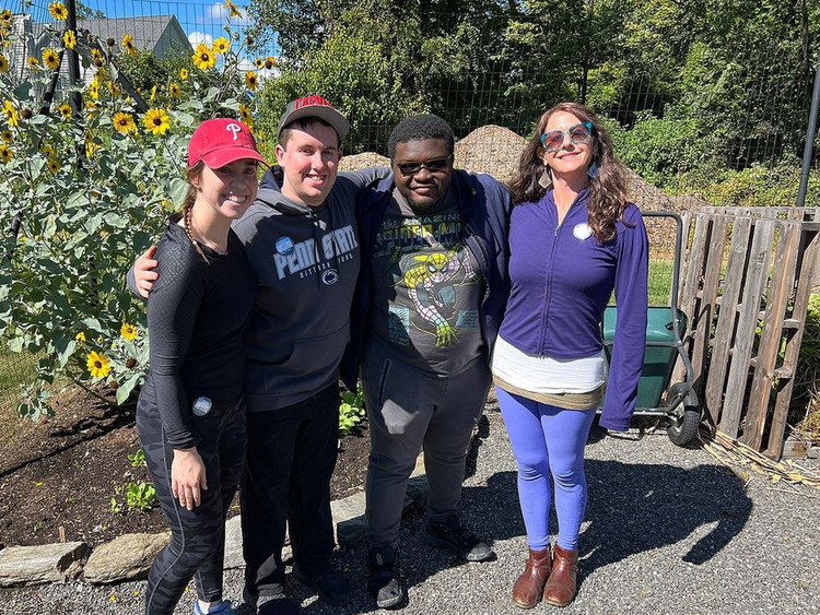 Students and garden manager standing in front of sun flowers