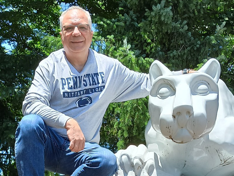 George Eleftherakis posing next to the Penn State Nittany Lion shrine