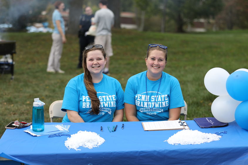 Two Penn State Brandywine volunteers sit at the registration table at the 2019 homecoming celebration.