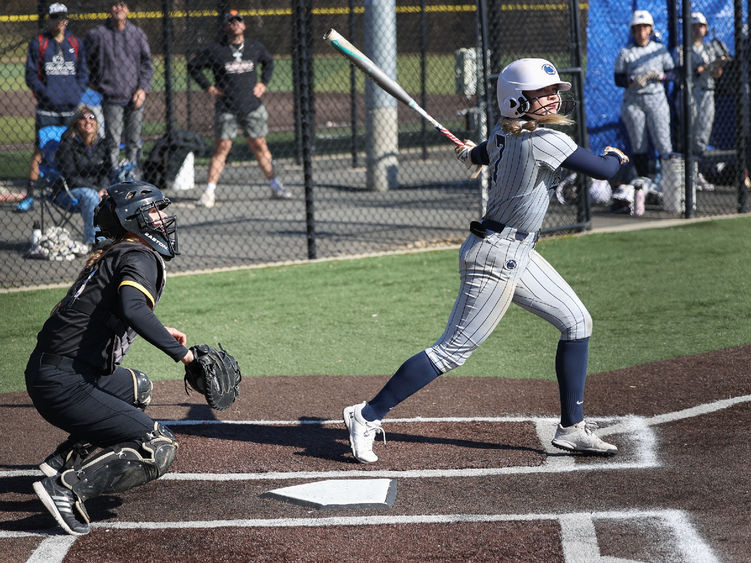 A female softball player swings the bat.