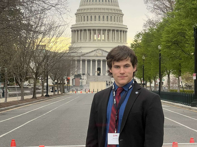 A male stands on a street in front of the U.S. Capitol