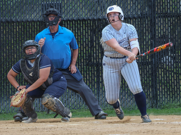 A female softball player looks ahead after hitting the ball.