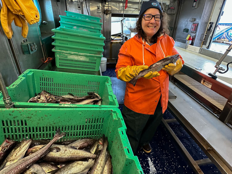 A woman on board a ship hold a fish.