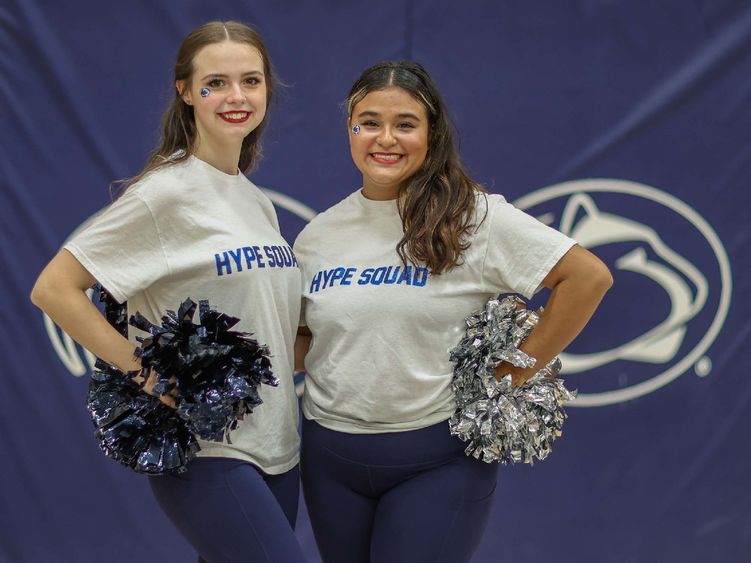 Two female students on the Hype Squad stand in the campus gym.