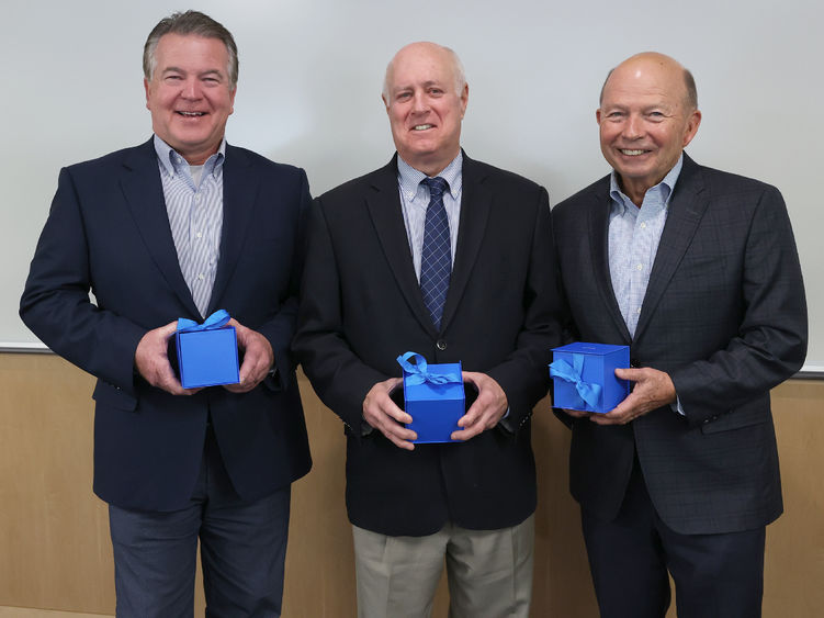 Three men hold boxes containing their gifts.