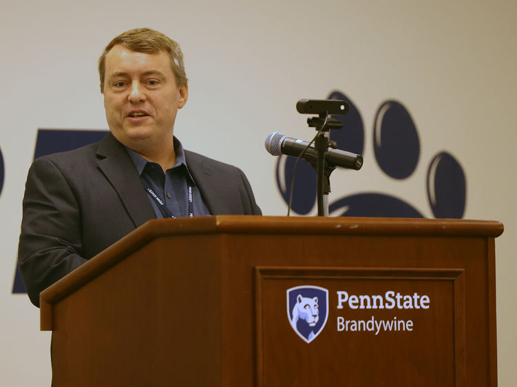 A man is speaking and standing behind a lectern.