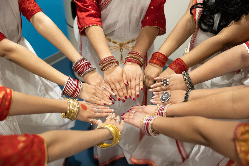 Students show their arms wearing many colorful bracelets and rings.