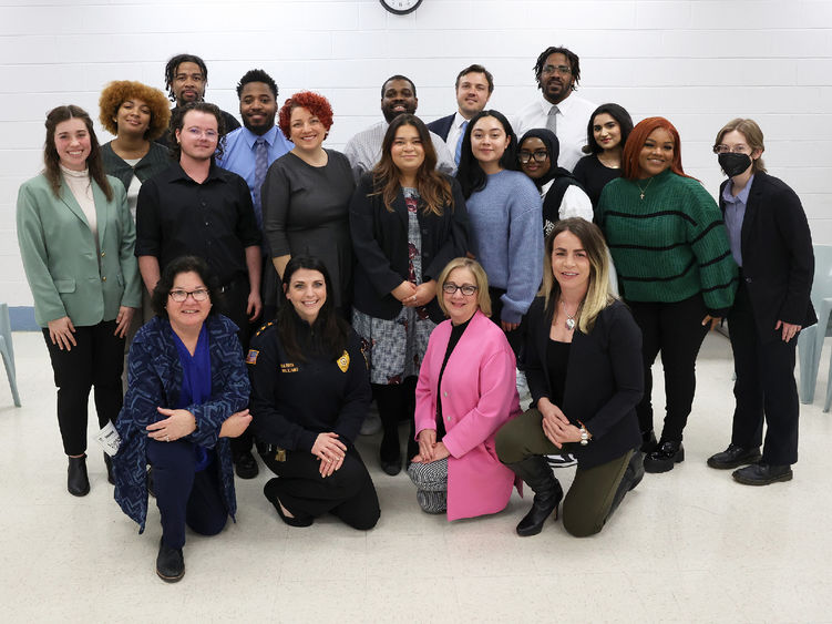 A group of people poses for a photo in front of a white wall.