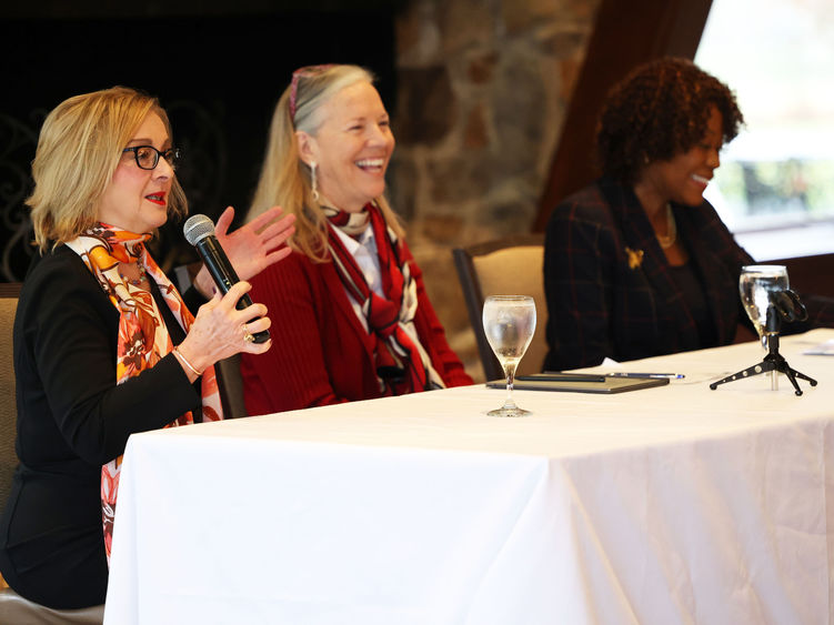 Three women sit at a table facing the audience.