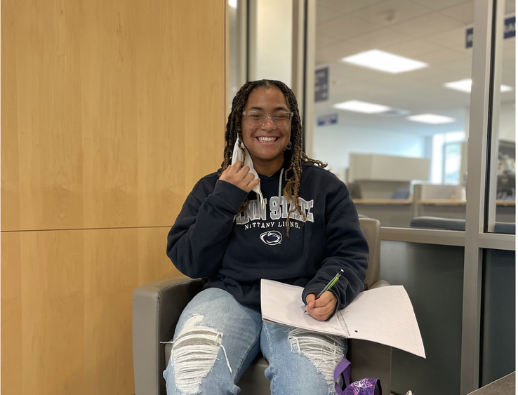 Students Sierra Coleman sits in a chair writing